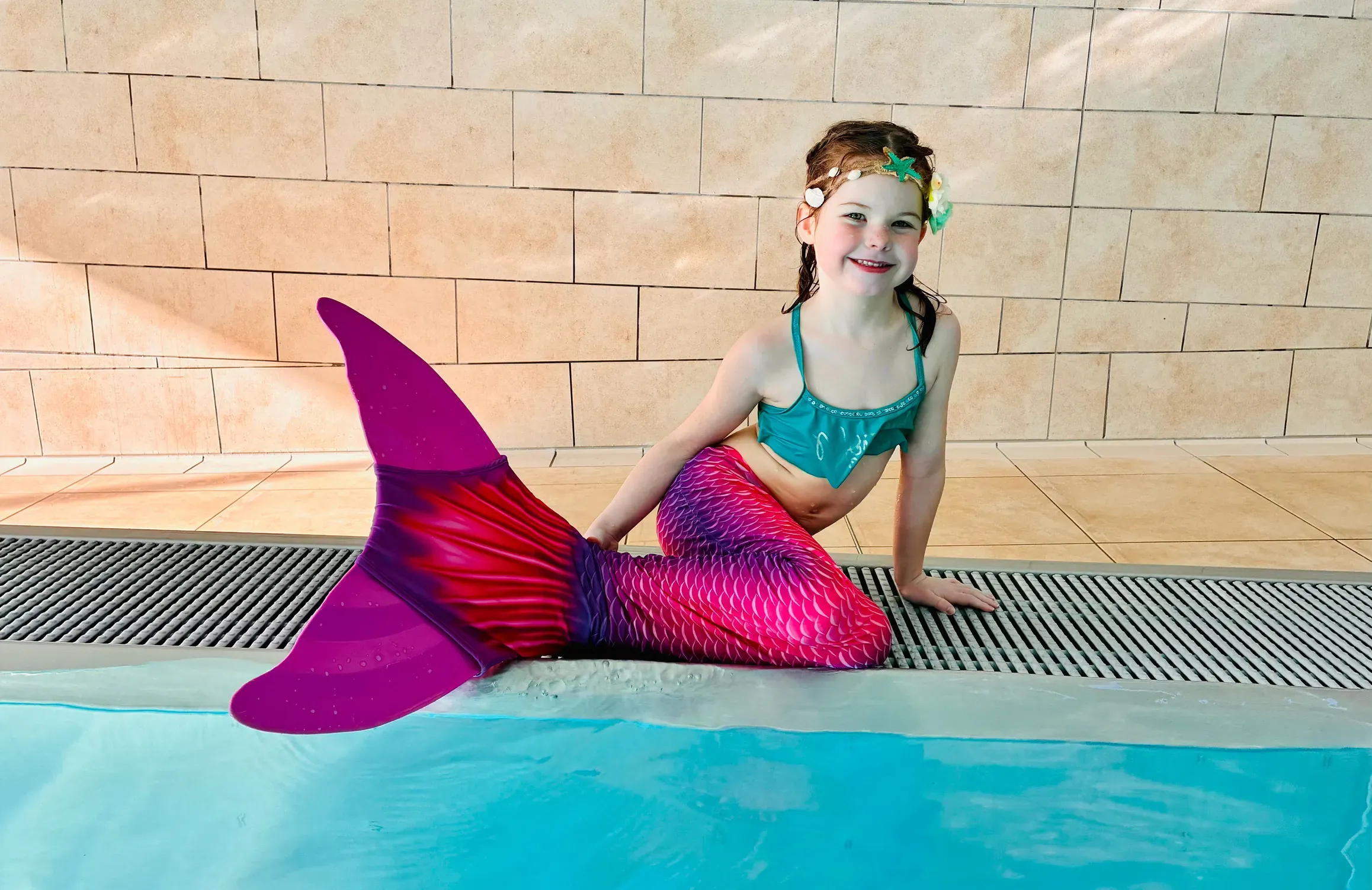 Kind mit Meerjungfrauenflosse und Glitzer-Make-up bei einer Nixenparty in der Aquarena