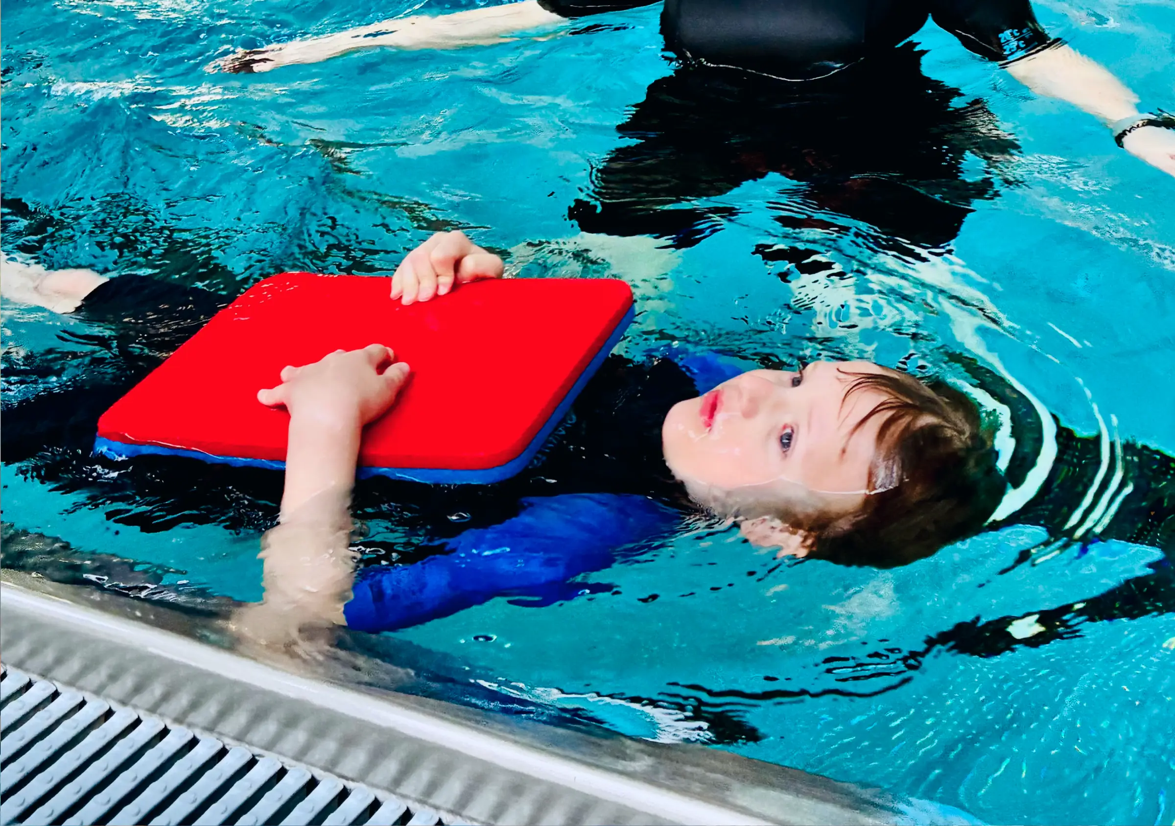 Kind schwimmt in Rückenlage mit Schwimmbrett in der Robbengruppe der Aquarena Neunkirchen-Seelscheid