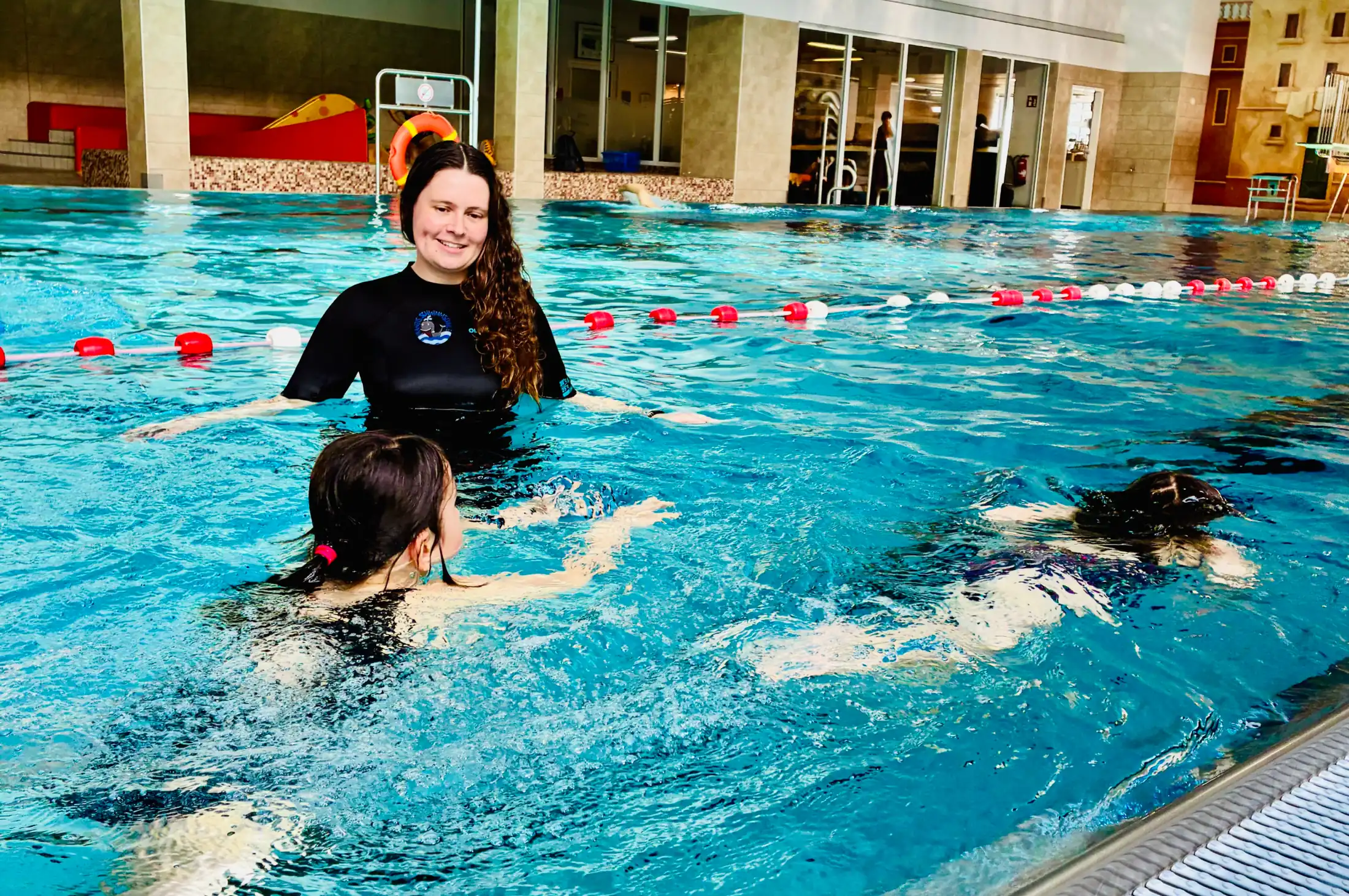 Trainerin begleitet ein Kind beim Techniktraining der Robbengruppe in der Aquarena Neunkirchen-Seelscheid