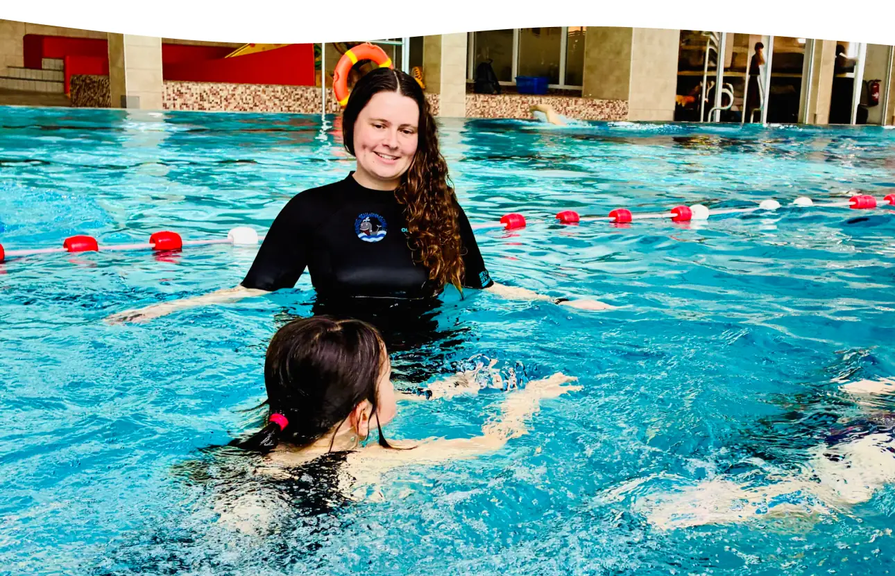 Trainerin begleitet ein Kind beim Techniktraining der Robbengruppe in der Aquarena Neunkirchen-Seelscheid