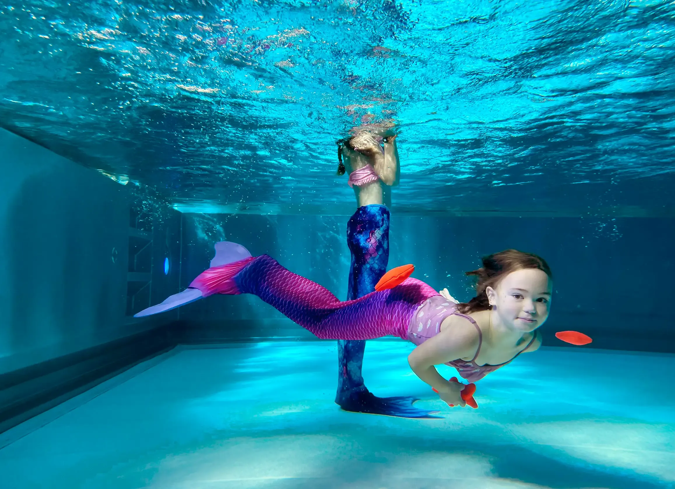 Kind taucht mit Monoflosse durch einen Reifen beim Schnuppermermaiding